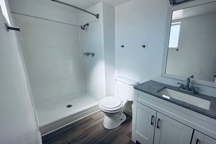 Sleek and modern bathroom featuring a large shower, elegant vanity with granite countertop, and stylish fixtures for a sophisticated touch.
