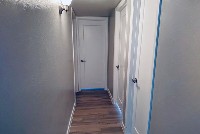 Bright and modern hallway with elegant wooden flooring and sleek white doors, exuding a stylish and welcoming atmosphere.