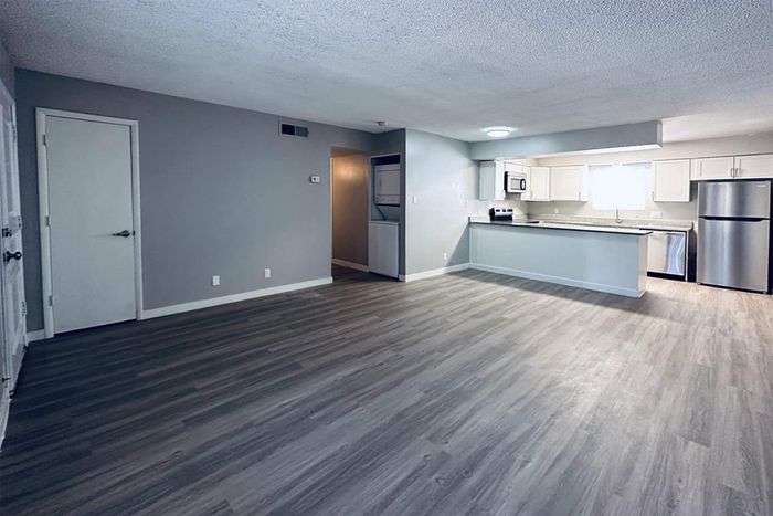 Modern open-plan living space with elegant wood flooring and a sleek kitchen featuring stainless steel appliances.