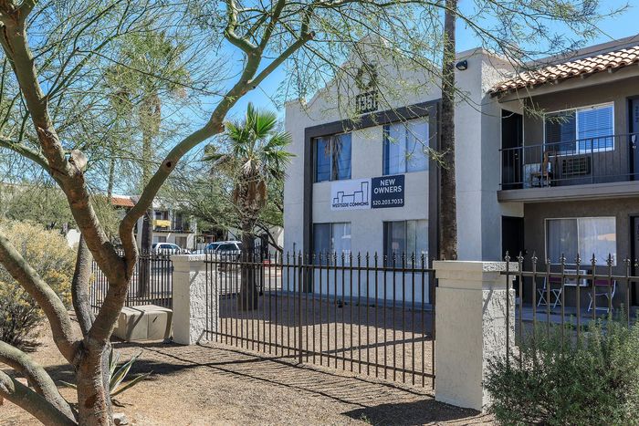Charming apartment complex with a modern exterior, fenced courtyard, and welcoming greenery, perfect for new homeowners.