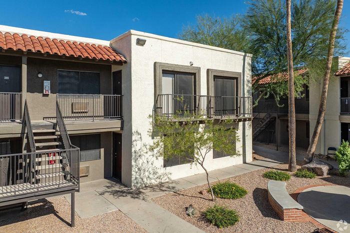 Charming apartment exterior with a classic terracotta roof, private balconies, and lush desert landscaping in a serene setting.