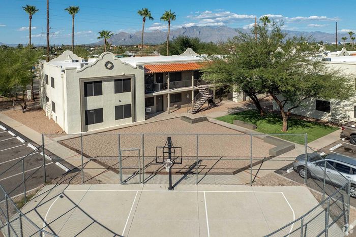 Charming apartment complex featuring a unique, two-story design with outdoor stairways, complemented by a scenic basketball court and beautifully landscaped surroundings, set against stunning mountain views.