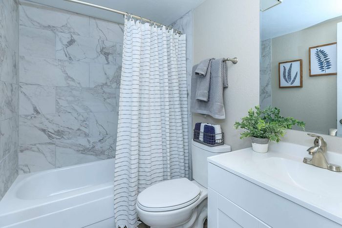 Elegant bathroom with modern marble tiles, sleek vanity, and inviting shower area. Includes tasteful decor and soft towels for a spa-like experience.