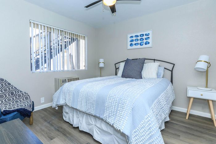 Charming bedroom featuring a cozy bed with textured bedding, modern side tables, ambient lighting, and stylish wall art under a ceiling fan.