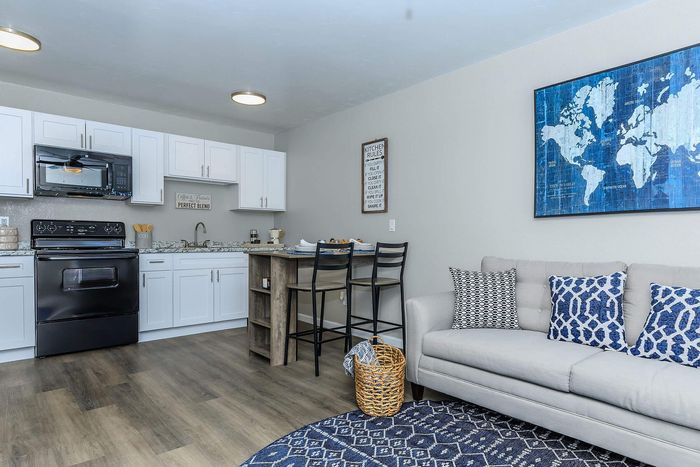Modern open-concept kitchen and living area with elegant decor, white cabinetry, and stylish lighting.