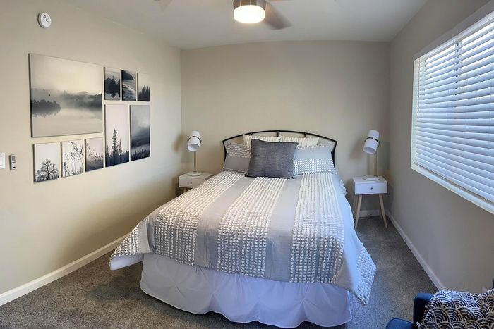 Cozy bedroom with a chic gray and white color scheme, featuring elegant wall art, soft lighting, and a comfortable bed inviting relaxation.