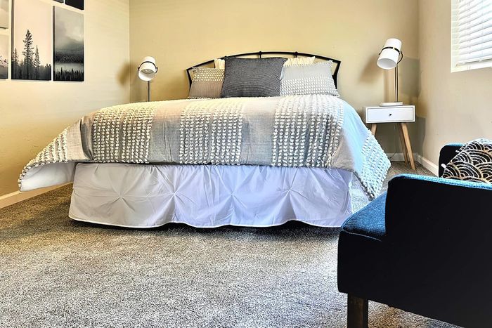 Cozy bedroom with elegant bedding, stylish lamps, and modern wall art, perfect for relaxation.
