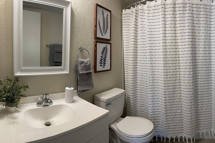 Modern bathroom featuring a sleek white vanity, elegant mirror, and stylish botanical wall art, creating a serene and inviting atmosphere.