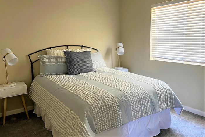 Bright and cozy bedroom with stylish decor, featuring a comfortable bed and modern lighting, bathed in natural sunlight.