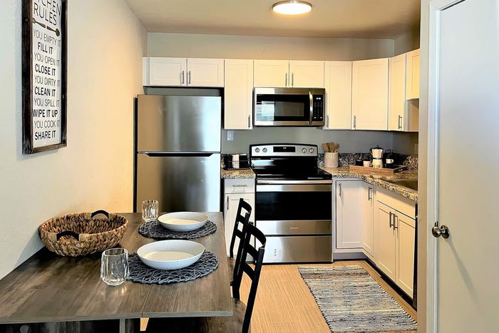 Modern kitchen with sleek stainless steel appliances, elegant granite countertops, and inviting dining setup.