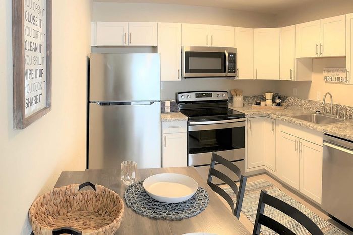 Chic and modern kitchen with sleek stainless steel appliances, elegant white cabinetry, and a granite countertop, offering a stylish and functional cooking space.