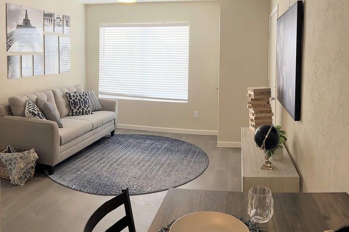 Bright and modern living room with cozy sofa, elegant artwork, and stylish decor, featuring a round carpet and large window for natural light.