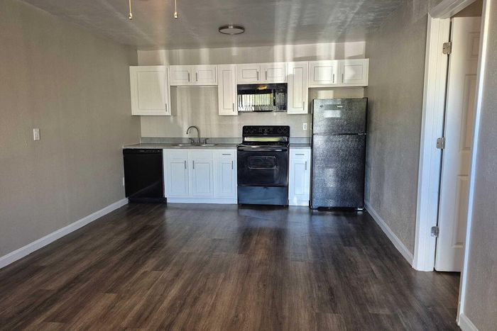Chic kitchen with modern appliances, sleek black and white cabinetry, and elegant wood flooring.