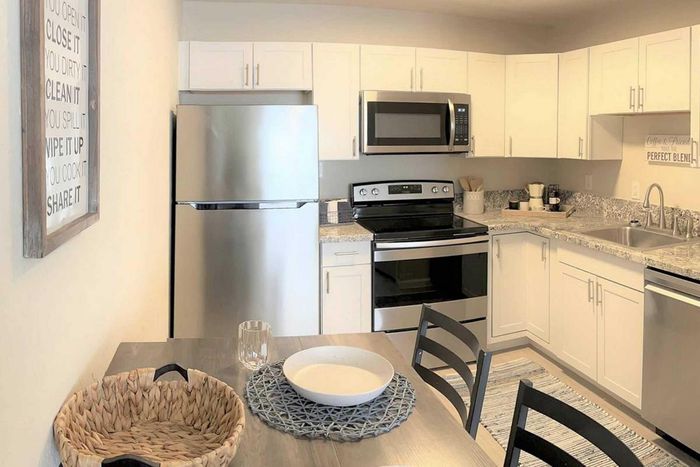 Contemporary kitchen with sleek stainless steel appliances, granite countertops, and elegant white cabinetry, creating a bright and inviting cooking space.