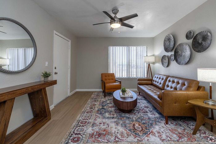 Contemporary living room with stylish leather furniture, elegant wall decor, and a vibrant patterned rug creating a cozy atmosphere.