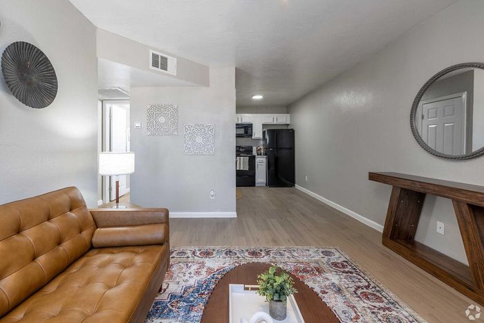 Bright and inviting living space featuring a modern kitchen, cozy sofa, and elegant decor with wooden flooring.