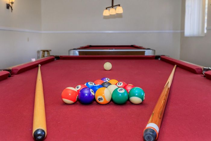 Elegant recreational room featuring a vibrant billiard table with colorful balls and cues under soft lighting.
