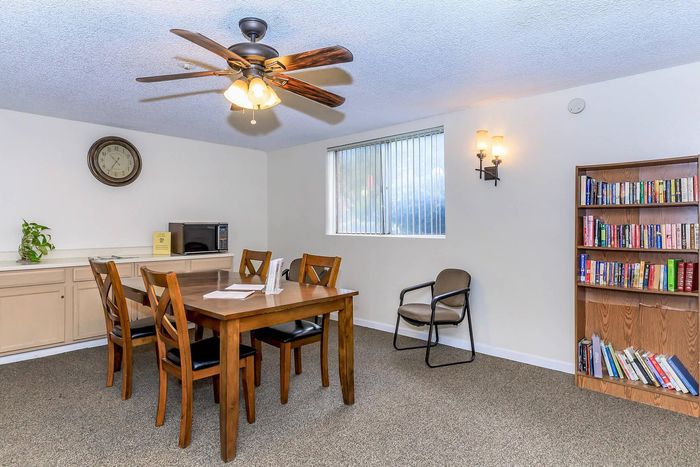 Charming dining area with a wooden table, elegant chairs, built-in storage, and a cozy bookshelf under warm lighting.