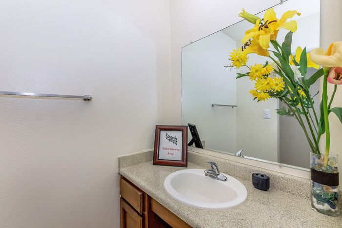 Bright, elegant bathroom with sleek countertop, vibrant yellow flowers, and a modern touch of style.