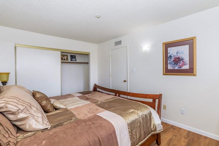 Cozy bedroom featuring a luxurious bed with elegant linens, warm lighting, and charming framed artwork.