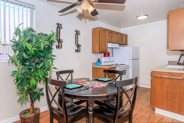 Charming kitchen and dining area featuring contemporary wood cabinetry, a sleek dining table with elegant chairs, and vibrant natural lighting.