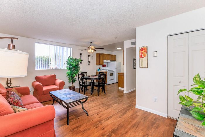 Cozy living area with vibrant orange seating, hardwood floors, and an open kitchen with modern amenities.