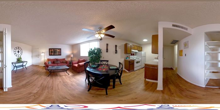 Charming open-plan living space with cozy seating, dining area, and a modern kitchen, enhanced by elegant wooden flooring and natural light.