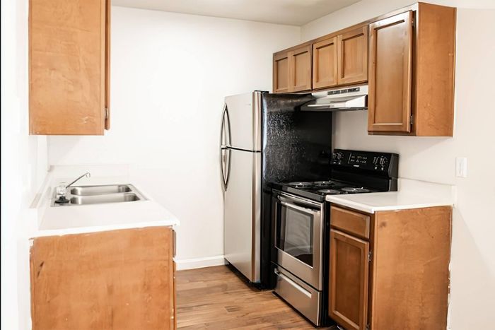 Charming kitchen with modern stainless steel appliances, sleek wooden cabinets, and elegant hardwood flooring.