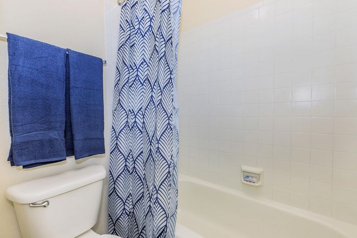 Modern bathroom featuring elegant blue and white shower curtain, pristine white tiles, and plush navy towels for a refreshing ambiance.