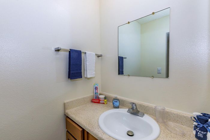 Bright and inviting bathroom with modern sink, elegant countertop, and stylish wall mirror, accented with vibrant towels and toiletries for a fresh living experience.