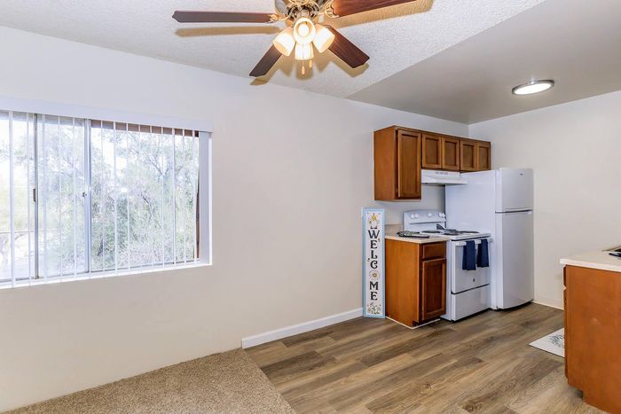 Charming apartment interior featuring a cozy kitchen with warm wood cabinets, modern appliances, and a ceiling fan, offering a bright and inviting space.
