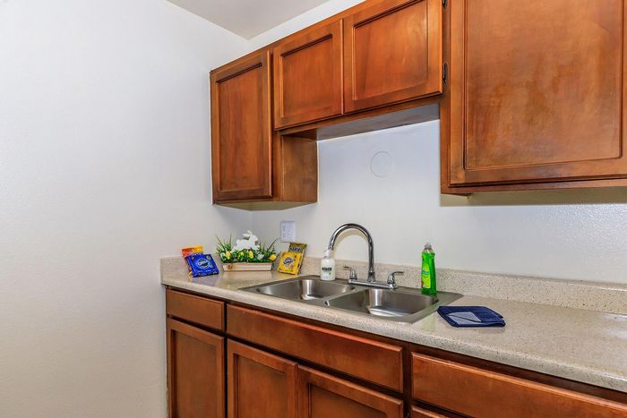 Charming kitchen with sleek double sink, polished countertops, and warm wooden cabinets, perfect for culinary enthusiasts.
