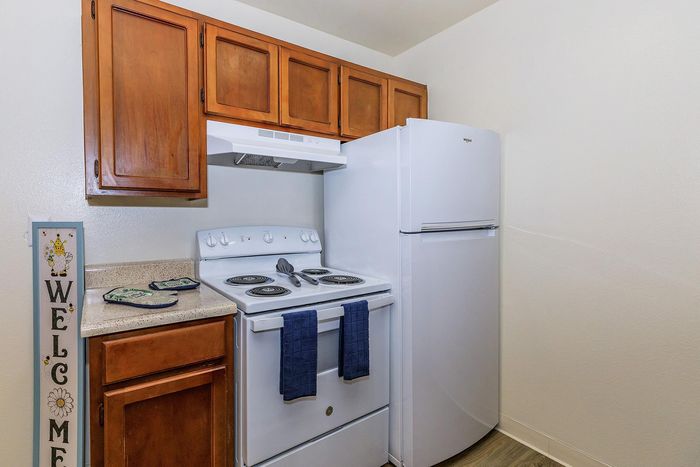 Charming kitchen with warm wooden cabinets, sleek white appliances, and a cozy countertop, perfect for creating culinary delights.