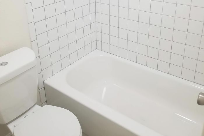 Bright and modern bathroom featuring a pristine white bathtub and tiled walls, offering a clean and relaxing space.