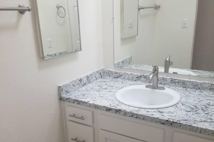Elegant bathroom with gleaming granite countertop, modern sink, and sleek fixtures on crisp white cabinets.