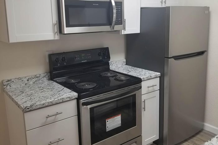 Modern kitchen with sleek stainless steel appliances, white cabinets, and elegant granite countertops.
