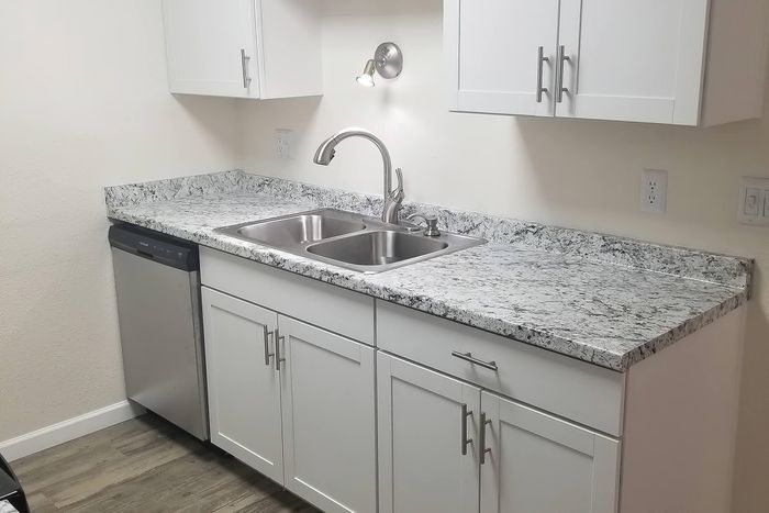 Sleek modern kitchen with granite countertops, stylish white cabinets, and a stainless steel dishwasher.
