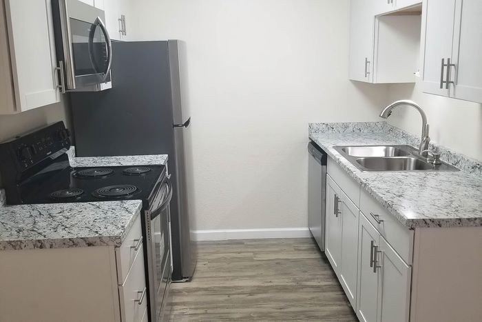 Modern kitchen with sleek stainless steel appliances, stylish granite countertops, and white cabinetry on elegant hardwood flooring.