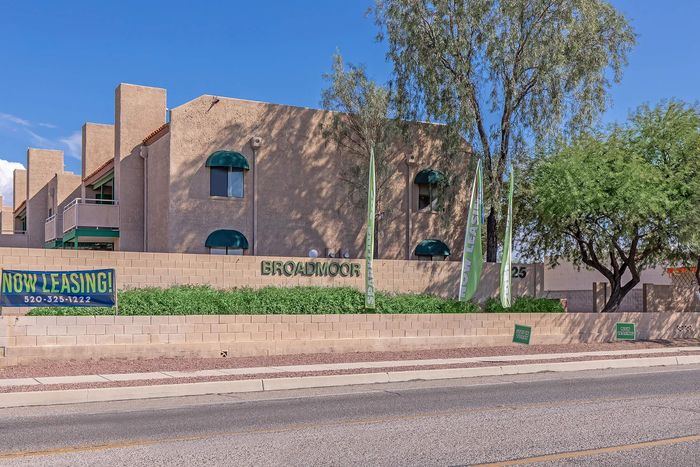 Broadmoor apartments showcasing stylish architecture with lush landscaping and prominent 'Now Leasing' signage, offering modern living spaces.