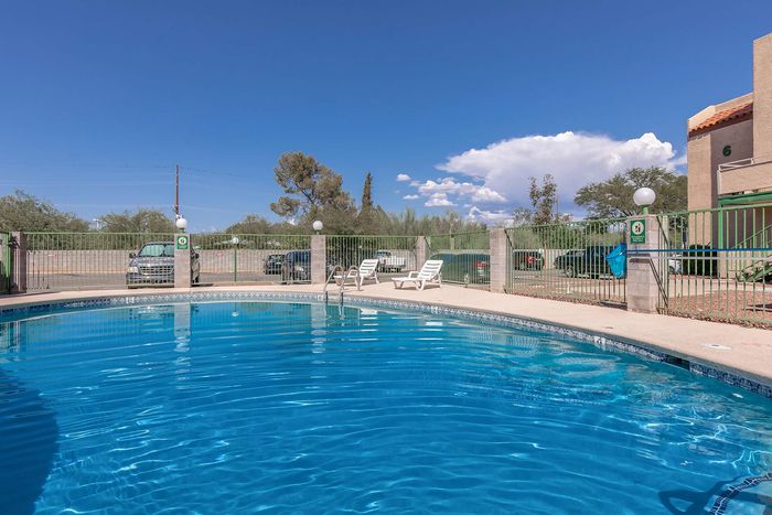 Inviting outdoor pool with serene blue water and poolside loungers, perfect for relaxation under a clear sky.