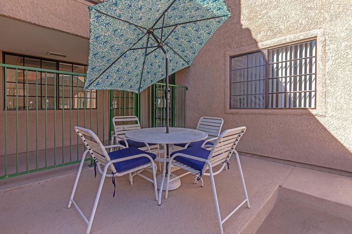 Charming patio featuring a round table with stylish blue-cushioned chairs and a vibrant umbrella, perfect for outdoor relaxation.