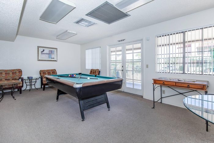 Chic and inviting game room with a pool table and elegant seating, featuring large windows for abundant natural light.