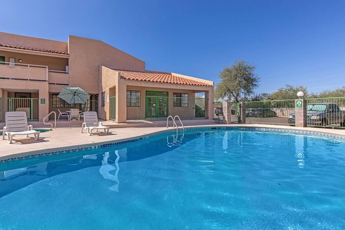 Inviting outdoor pool area with lounge chairs and shaded seating, perfect for relaxation under the sunny sky.