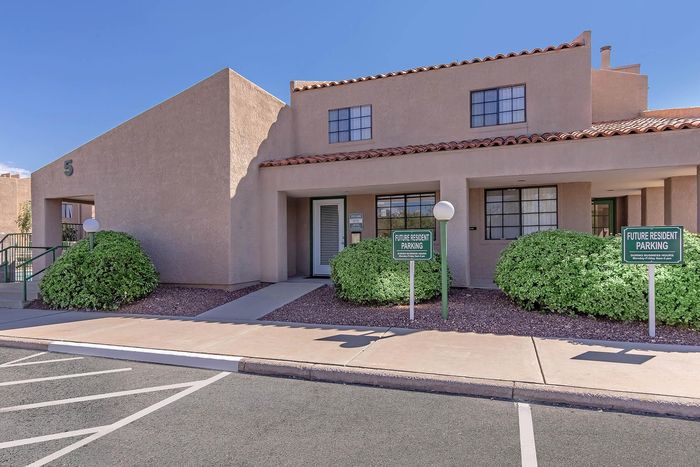 Inviting apartment complex with modern architecture, lush greenery, and designated future resident parking.