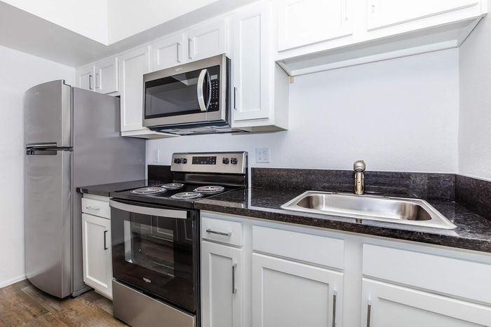 Modern kitchen with sleek stainless steel appliances, white cabinetry, and elegant dark countertops.