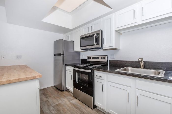Bright and modern kitchen with sleek stainless steel appliances, elegant white cabinetry, and stylish wood flooring.