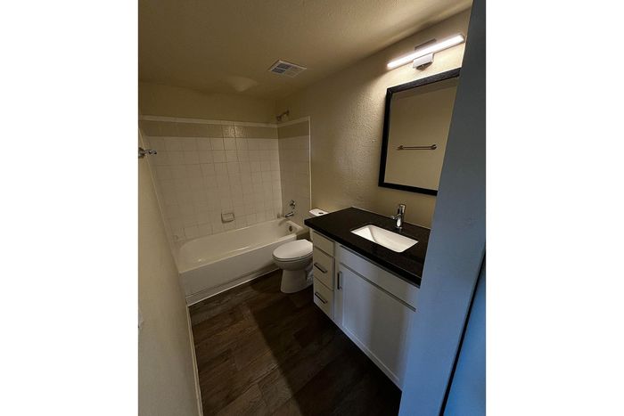 Chic and modern bathroom featuring elegant dark countertops, sleek white cabinetry, and a spacious bathtub, perfect for relaxation.