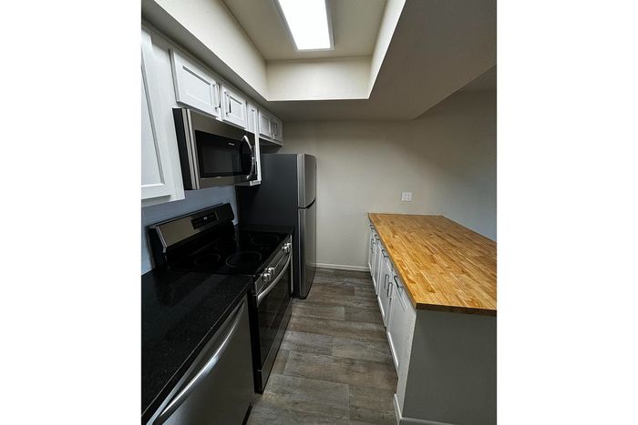 Modern kitchen with sleek stainless steel appliances, elegant black countertops, and spacious wooden cabinetry.