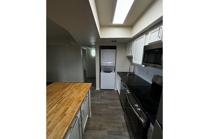 Modern kitchen with sleek countertops, wood-accented island, and integrated laundry appliances for convenience.