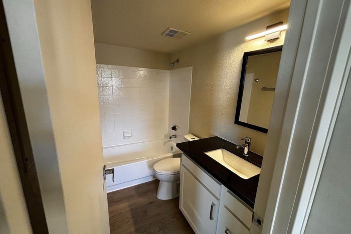 Elegant bathroom featuring a sleek black countertop, modern fixtures, and a pristine bathtub with bright tile backsplash.